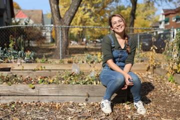 A woman sits near a flower box in Autum