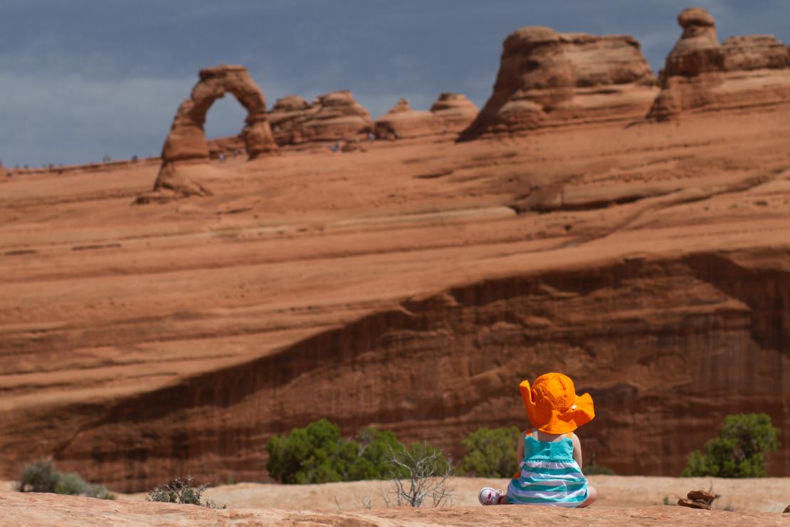 A small child views red geological structures