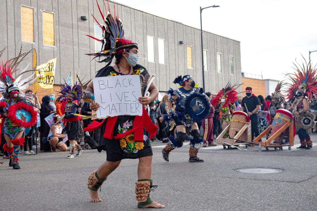 A native dancer holding a Black Lives Matter sign